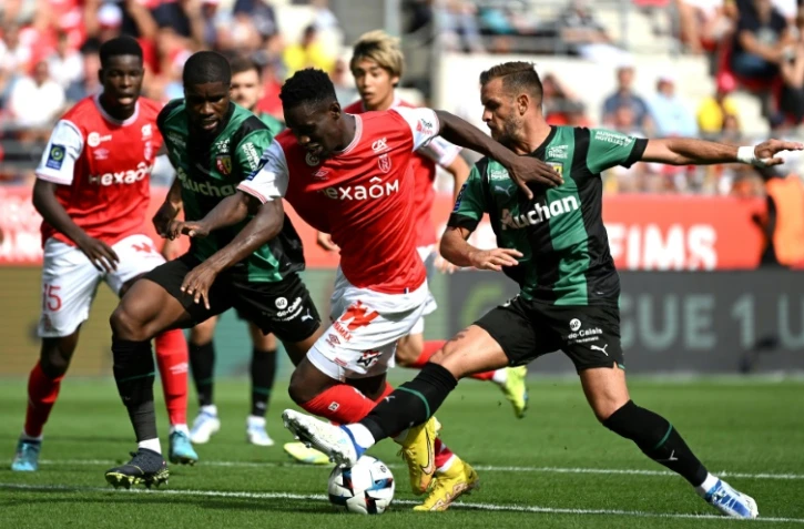L'attaquant de Reims Folarin Balogun (c) tente un passage au milieu des Lensois Kavin Danso (g) et Jonathan Gradit (d), le 4 septembre 2022 à Reims   