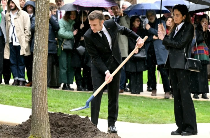 Le président Emmanuel Macron (g) ajoute de la terre à un chêne dédié à Ilan Halimi, en présence de la sœur d'Ilan, Anne-Laure Abitbol (d), lors d'une cérémonie commémorant le 20e anniversaire de son assassinat, à l'Élysée, le 13 février 2026 à Paris