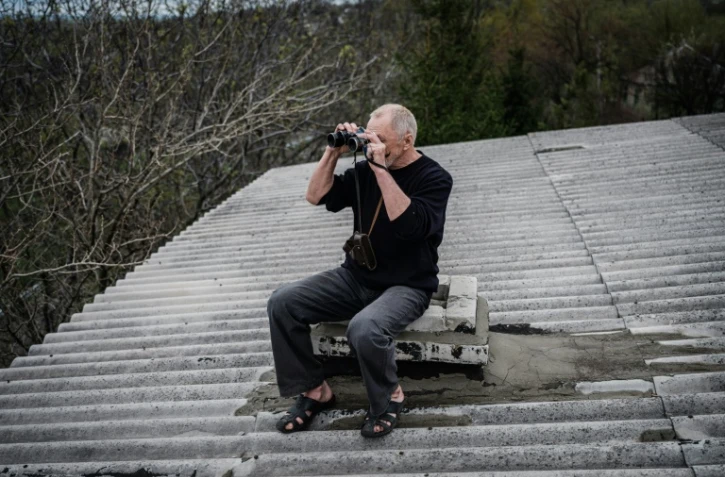 Mykola, ingénieur ukrainien à la retraite observe les positions russes avec ses jumelles depuis le toit de sa maison à Lyssychansk, dans l'est de l'Ukraine, le 22 avril 2022