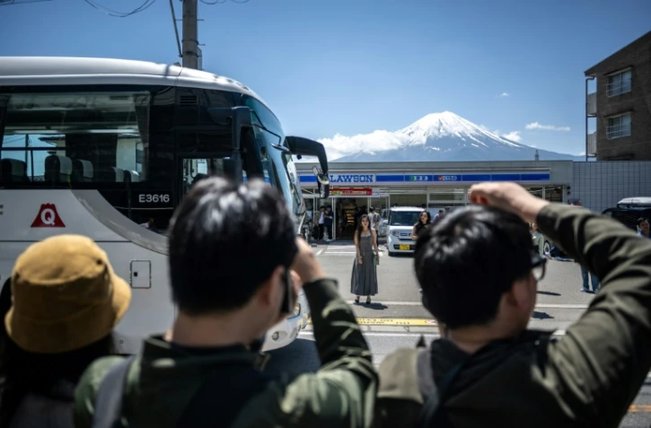 Des touristes photographient le mont Fuji avant l'installation d'un vaste filet pour cacher la vue, le 3 mai 2024 Ă Fujikawaguchiko, au Japon