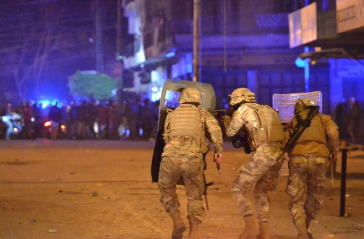 Des forces de sécurité libanaises prennent position durant des affrontements avec les manifestants anti-gouvernementaux le 27 janvier 2021 à Tripoli, dans le nord du Liban