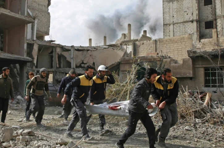 Des secouristes transportent une victime d'un raid du régime syrien dans la localité de Hazeh dans la Ghouta orientale, le 8 février 2018