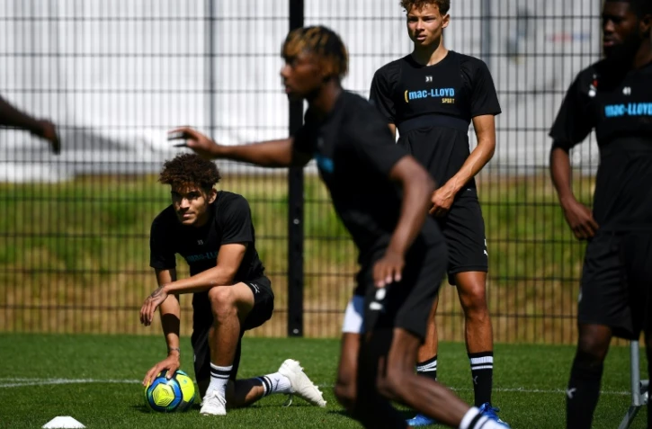 Le défenseur d'Amiens Valentin Gendrey (g) et certains de ses coéquipiers prennent part à la reprise de l'entraînement sur un terrain situé près du Stade de la Licorne, à Amiens le 25 juin 2020.