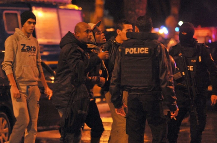 Des policiers encadrent des proches des victimes d'un attentat contre un bus de la sécurité présidentielle, le 24 novembre 2015 à Tunis