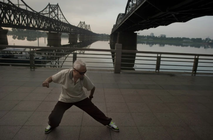 Un homme fait du Tai Chi au lever du soleil le 5 juillet 2017 à Dandong, près du Pont de l'Amitié reliant la Chine à la Corée du Nord