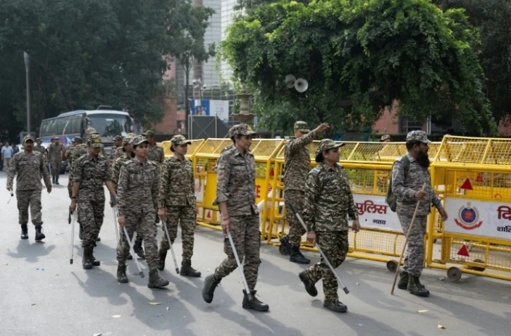 Les membres des forces de sécurité arrivent pour prendre leur poste à un point de contrôle temporaire à New Delhi, le 11 octobre 2026