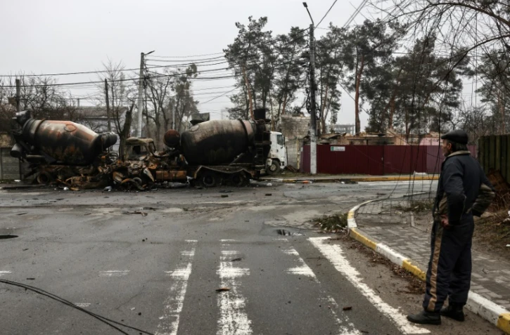 Un homme regarde des camions brûlés dans une rue d'Irpin, près de Kiev, le 1er avril 2022