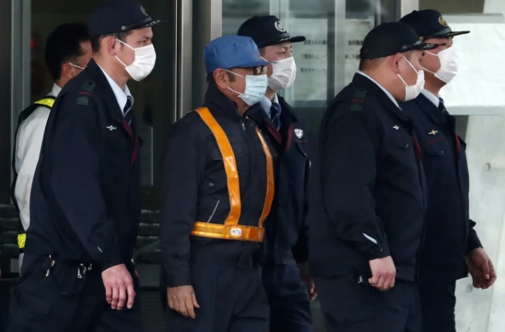 L'ancien patron de Renault Carlos Ghosn (c) est escorté à sa sortie de détention suite au versement d'une caution, à Tokyo, le 6 mars 2019