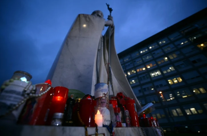 Des bougies sont allumées devant une statue de Jean Paul II à l'extérieur de l'hôpital Gemelli à Rome où le pape François est hospitalisé, le 12 mars 2025