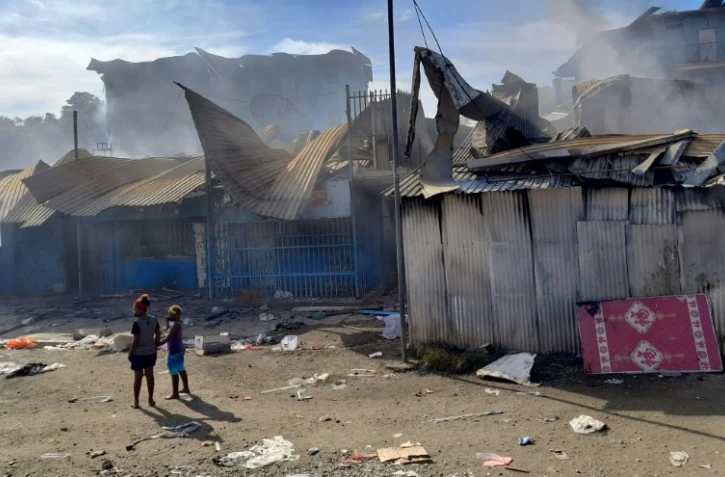 De la fumée s'élève de bâtisses dans le quartier chinois d'Honiara, le 26 novembre 2021