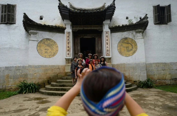 Des touristes posent le 26 octobre 2018 devant un ancien palais Hmong à Dong Van, dans le nord du Vietnam