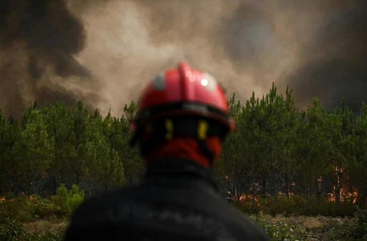Un pompier regarde des pins en feu près de Saint-Magne, dans le sud-ouest de la France, le 11 août 2022 