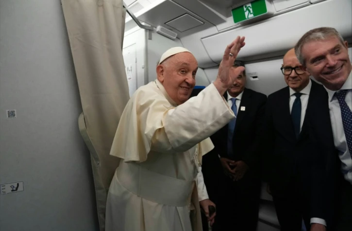 Le pape François fait un geste de la main le 2 septembre 2024 à bord de l'avion à destination de l'Indonésie