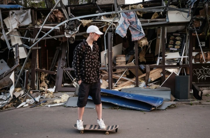 Roman Kovalenko, 18 ans, fait du skateboard près d'un commerce de Kramatrosk (Ukraine) détruit par un missile, le 5 mai 2022