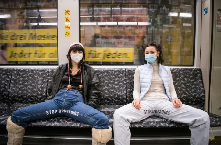 Elena Buscaino (d) et Mina Bonakdar deux militantes féministes écartent leur jambes pour dénoncer l'attitude des hommes qui s'étalent jambes écartés dans le métro à Berlin, le 5 février 2021
