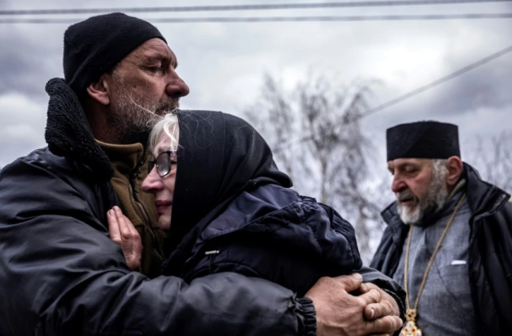 Les proches d'un civil exhumé de son jardin dans le village de Gostomel, région de Kiev, le 12 avril 2022