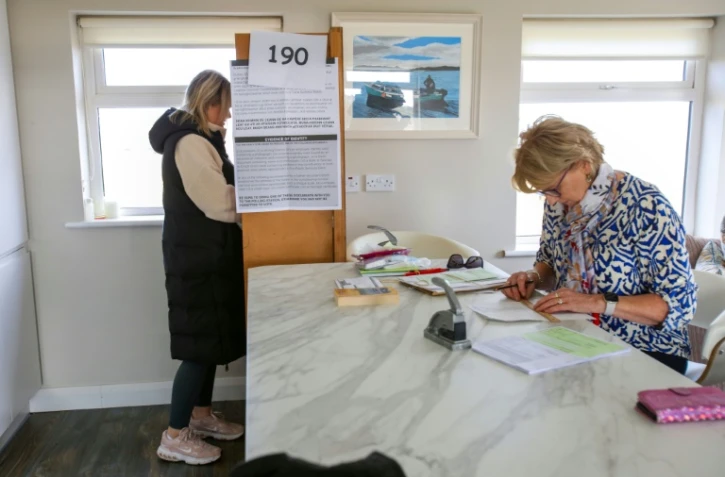 Une électrice (g) dans un bureau de vote lors du référendum destiné à moderniser les références aux femmes et à la famille dans la Constitution irlandaise, sur l'île de Gola, au large de la côte du Donegal, à l'ouest de l'Irlande, le 8 mars 2024