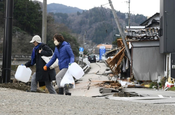 Des habitants transportent des bidons d'eau après un séisme meurtrier, à Wajima au Japon le 5 janvier 2024