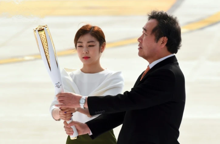 Le Premier ministre sud-coréen Lee Nak-Yon (d) et la médaille d'or du patinage artistique Kim Yu-Na portent la flamme olympique, le 1er novembre 2017 à l'aéroport de Séoul lors d'une cérémonie pour son arrivée en Corée du Sud
