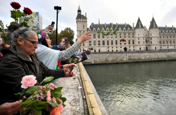 Des femmes lancent des roses dans la Seine depuis le pont Neuf à Paris, en souvenir des dizaines de manifestants algériens tués durant la répression du 17 octobre 1961, le 17 octobre 2021
