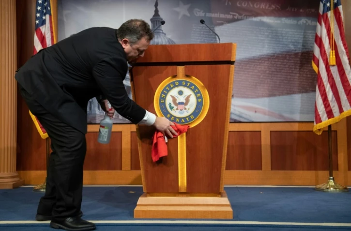 Un employé désinfecte le pupitre de la salle de presse du Sénat américain,
à Washington, le 17 mars 2020