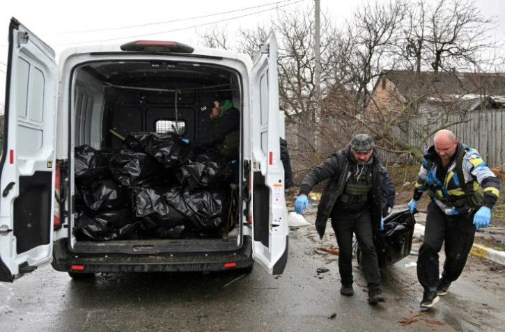 Des employés municipaux chargent un corps dans une camionette le 3 avril 2022 à Boutcha, ville au nord-ouest de Kiev où les autorités ukrainiennes accusent les forces russes d'avoir commis un massacre