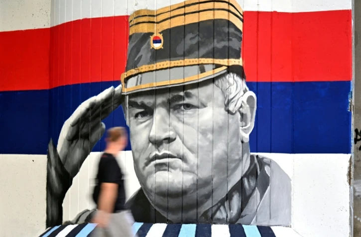 Un homme passe devant une fresque murale représentant l'ancien chef militaire des Serbes de Bosnie, Ratko Mladić, le 6 septembre 2026 à Belgrade, en Serbie, dont l'inhumation est prévue le 7 septembre 2026 au cimetière de Topčider à Belgrade, sur fond de critiques de l'UE concernant la "glorification" d'un criminel de guerre condamné pour génocide