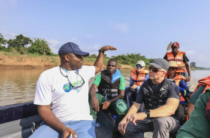 Aristide Takoukam Kamla (g), docteur en biologie marine, spécialiste du lamantin d'Afrique, s'entretient avec des touristes et d'autres biologistes sur un bateau à Dizangue, le 10 décembre 2024 au Cameroun