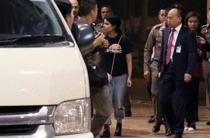 La jeune Saoudienne Rahaf Mohammed al-Qanun (C) est escortée vers un véhicule par un responsable thaïlandais de l'immigration et des délégués du Haut commissariat aux réfugiés de l'ONU, à l'aéroport Suvarnabhumi de Bangkok, le 7 janvier 2019