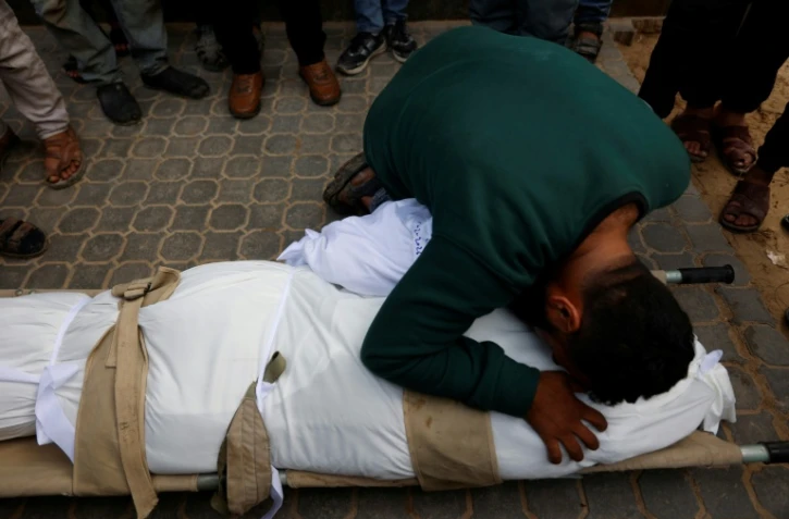 Un homme prosté sur le corps d'une personne tuée dans une frappe israélienne, à l'hôpital Al-Chifa le 4 février 2026