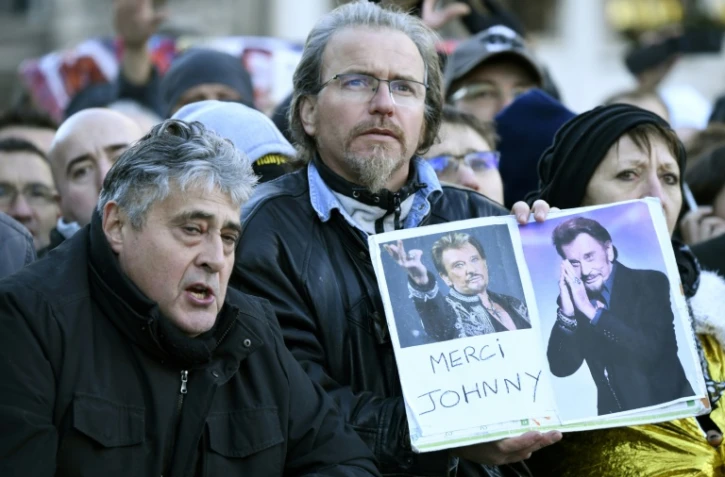 Des fans avec des portraits du chanteur "Merci Johnny" attendent devant l'Eglise de la Madeleine, le 9 décembre 2017 