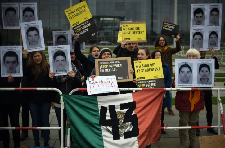 Des membres de l'organisation humanitaire Amnesty International, brandissent des photos d'étudiants disparus au Mexique, lors d'une manifestation à Berlin, devant la chancellerie, le 12 avril 2016
