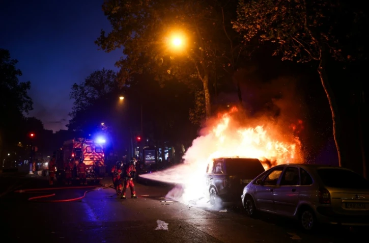 Les pompiers éteignent un véhicule en feu à Paris, lors de la manifestation contre la "vie chère", le 17 octobre 2026
