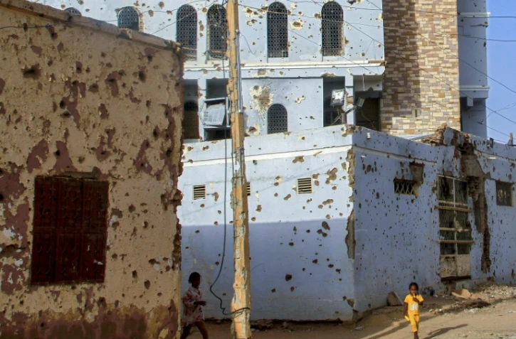 Des enfants soudanais marchent à côté de bâtiments criblés de balles à Omdourman la proche banlieue de Khartoum, le 20 mars 2025