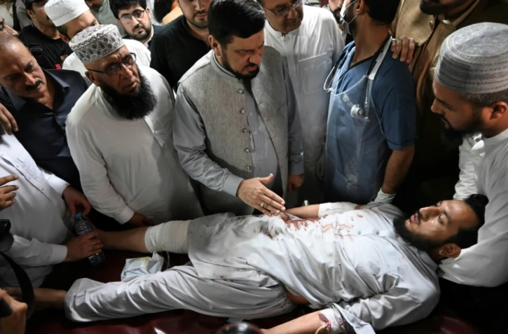 Le gouverneur de la province de Khyber Pakhtunkhwa, Haji Ghulam Ali (centre), réconforte un homme blessé lors de l'attentat suicide contre un meeting politique, le 30 juillet 2023 dans un hôpital de Peshawar (Pakistan)