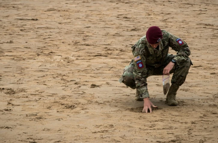 Un soldat américain recueille du sable à Omaha Beach, en Normandie, le 5 juin 2019