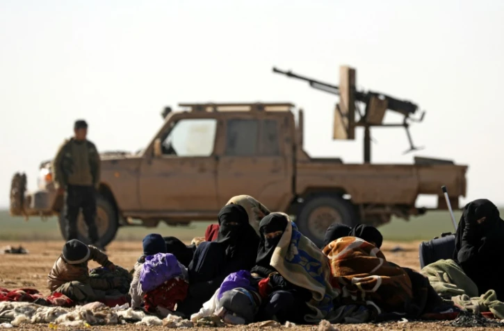 Des civils ayant fui les combats contre le groupe Etat islamique (EI) dans son ultime réduit de Syrie, et derrière eux un combattant des Forces démocratiques syriennes (SDF), près du village de Baghouz, le 3 février 2019