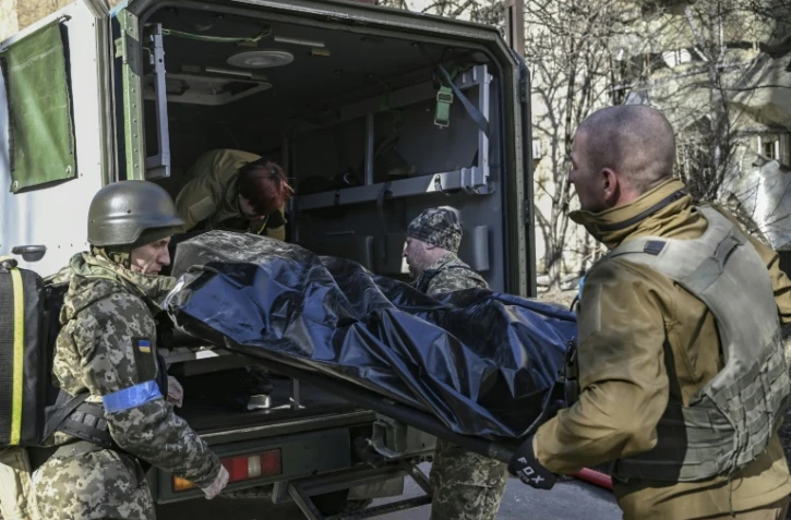 Des militaires ukrainiens évacuent le corps d'un soldat après une frappe russe, à Kiev, le 22 mars 2022