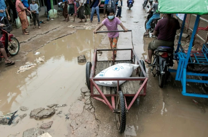 Une enfant pousse un chariot avec un sac de riz le 21 mai 2021, lors d'une distribution du PAM dans une banlieue de Rangoun