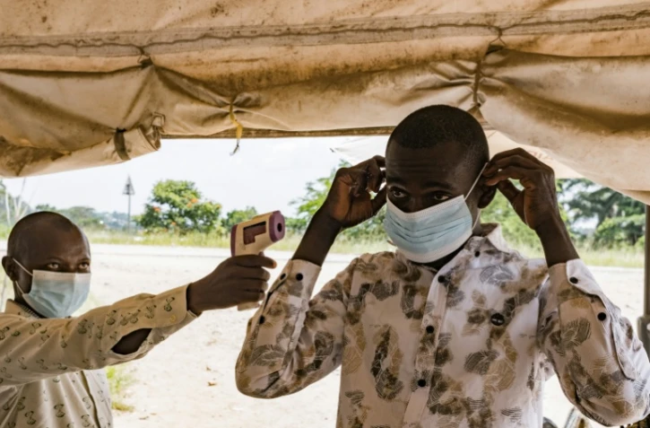 Un agent sanitaire à la frontière du poste de Busunga, entre l'Ouganda et la République démocratique du Congo, prend la température d'un voyageur à l'aide d'un thermomètre infrarouge sans contact à Bundibugyo, le 18 mai 2026.