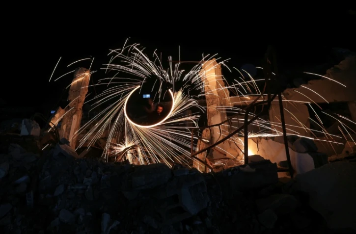 Des Palestiniens déplacés allument des feux d'artifice pour célébrer le début du mois du ramadan, dans un camp du centre de la bande de Gaza, le 17 février 2026