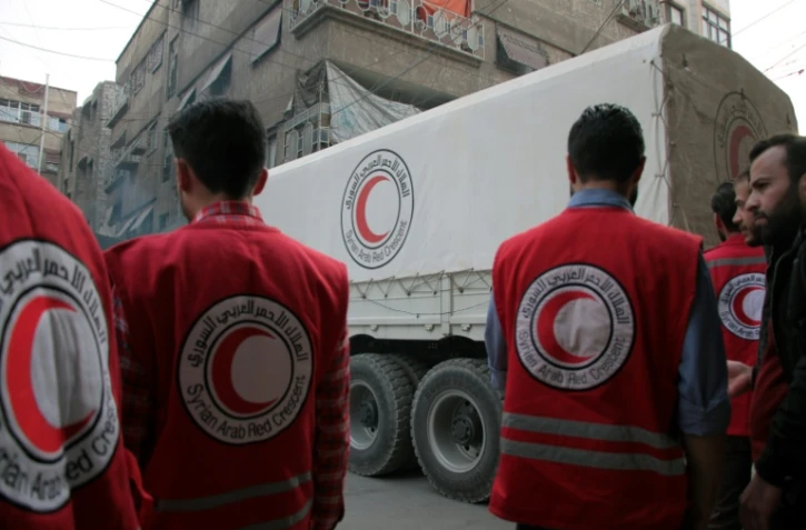Des membres de la Croix-Rouge syrienne s'apprêtent à décharger des camions transportant des cartons d'aides humanitaires, le 12 novembre 2017 à Douma, dans la Ghouta orientale