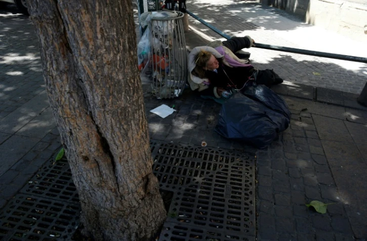 Une femme sans abri allongée sur le bitume à l'ombre d'un arbre, le 19 juillet 2016 à Paris