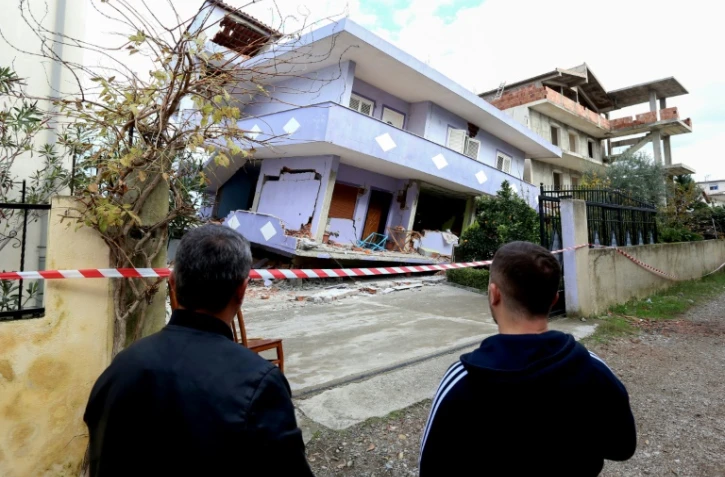 Des Albanais observent une maison effondrée le 28 novembre 2019 à Durres sur la côte Adriatique après un séisme meurtrier