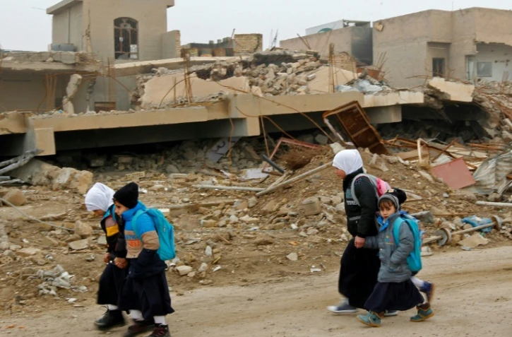Des enfants irakiens marchent dans un quartier en ruines à Fallouja, en Irak, le 29 décembre 2016