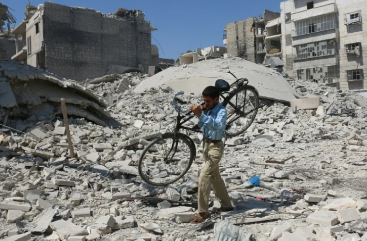 Un homme transporte un vélo parmi les ruines de bâtiments bombardés dans le nord d'Alep, le 11 septembre 2016
