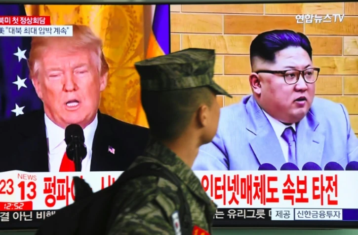 Un soldat sud-coréen passe devant un écran de télévision montrant des photographies du président américain Donald Trump (G) et du dirigeant nord-coréen Kim Jong Un dans une gare de Séoul, le 9 mars 2018