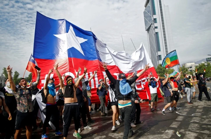 Des manifestants agitant un drapeau géant chilien, à Santiago du Chili le 23 octobre 2019