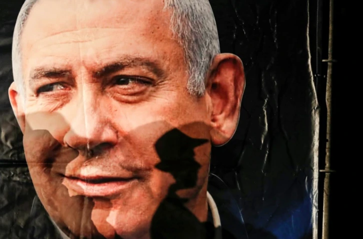 L'ombre d'un passant se projette sur un portrait du Premier ministre israélien Benjamin Netanyahu, à Jérusalem, le 11 décembre 2019