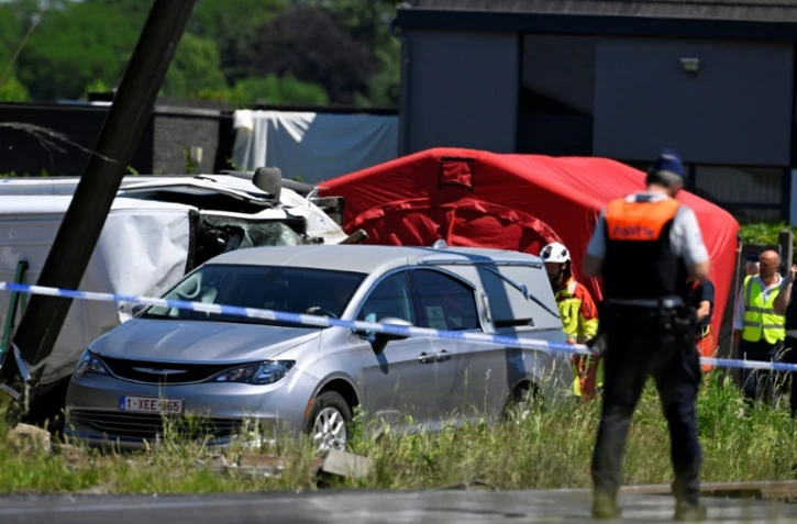 Un corbillard stationné sur le site d'un accident entre un train et un bus scolaire, au passage à niveau de Vierhuizen à Buggenhout, au nord de Bruxelles, le 26 mai 2026 en Belgique